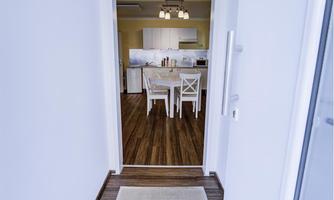 A bright hallway with a carpet leads into an open living and dining area. The kitchen is well-equipped and inviting.