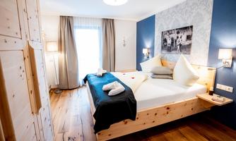 A cozy bedroom with a large bed and modern wooden furniture. The walls are painted in soft colors, and there is plenty of daylight coming through the window.