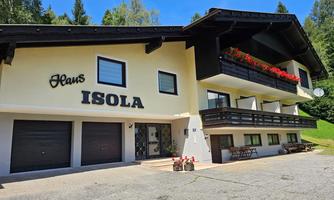 A charming building with the inscription "Haus Isola". The facade is bright, with flower boxes and a lovely entrance area.