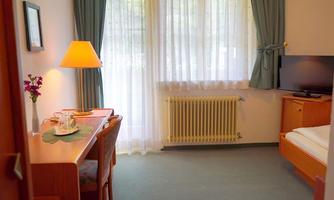 A cozy room with a table, chairs, and a television. The window is bright and lets in a lot of daylight.