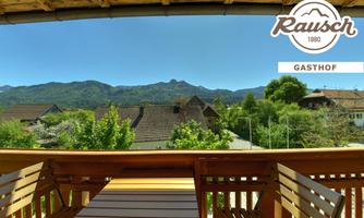 A beautiful view from the balcony of green mountains and houses. The sky is clear and blue.