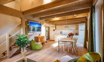 A modern, bright living room with a wooden ceiling and open space. There is a kitchen, a dining table, as well as cozy seating options.