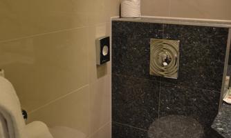 A modern bathroom with a toilet and a sink. The walls are brightly and elegantly tiled.