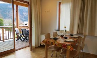 A cozy dining area with a table and chairs. Large windows offer a view of the terrace and the landscape outside.