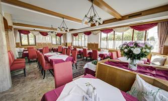 An inviting restaurant with red chairs and white tablecloths. Large windows let in plenty of light and create a cozy atmosphere.