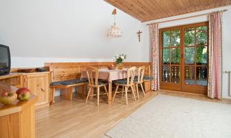 A cozy dining area with wooden furniture and a large window. The decor is rustic and inviting, with a view of the outdoors.