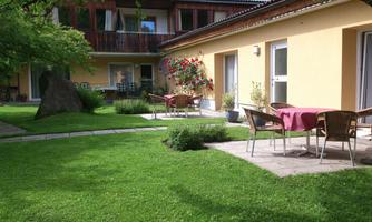 An inviting garden with lawn and patio furniture. The yellow facade of the building creates a warm atmosphere.