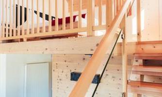 A modern interior design with a wooden staircase and an attractive railing. The upper area features a bedroom with minimalist decor.