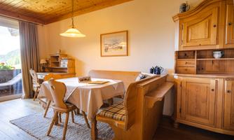 A cozy dining area with wooden-colored furniture. The table is set and there is pleasant lighting.