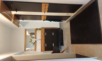 A modern hallway with a black cabinet and a mirror. There are flower vases and a rug on the floor.