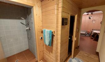 A rustic bathroom with a shower and a sauna. The walls are made of wood, and there is a blue towel on the wall.