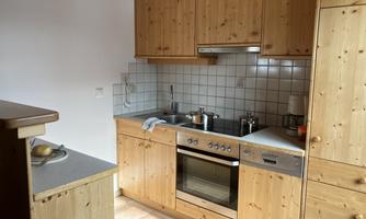 A modern kitchen with wooden cabinets and ceramic tiles. It is well equipped with a stove, sink, and cooking utensils.