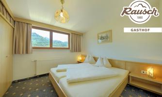 A cozy room with two beds and bright wooden details. Large windows offer a view of the surrounding landscape.