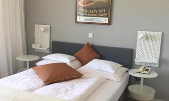 A modern bedroom with a large bed and two pillows. A decorative picture hangs on the wall, and there are two nightstands beside the bed.