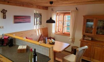 A cozy kitchen with wooden ceilings and furniture. A dining area with a couch, a table, and decorative elements.