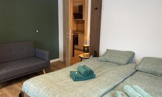 A cozy bedroom with a double bed and a sofa. The walls are painted in soft colors, and fresh towels are ready.