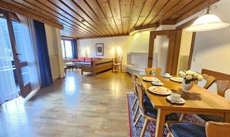 A cozy room with wooden floor and ceiling. A table with dishes and a seating area are also available.