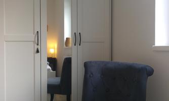 A cozy room with a blue chair and a white cabinet. In the background, soft lighting is visible.