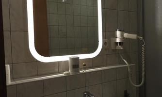 A modern bathroom with a lit mirror. The sink is in front of bright tiles.
