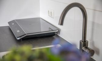 Modern induction cooktop in the kitchen unit. Ideal for preparing small meals or a cozy dinner by yourself.