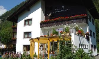 A charming building with a balcony full of flowers. In the foreground, bicycles and a cozy outdoor area can be seen.