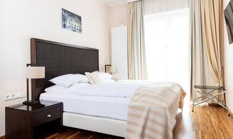 A modern bedroom with a large bed and soft color tones. Large windows let in plenty of light and create an inviting atmosphere.