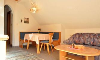 A cozy living space with a dining table and chairs. On the other side, there is a couch and a coffee table.