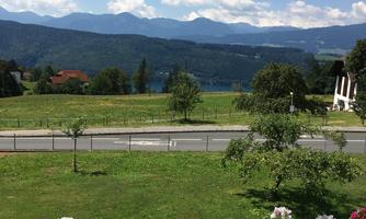 A picturesque landscape with mountains in the background and a calm lake. Blooming flowers adorn the balcony in the foreground.