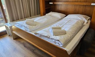 A cozy bedroom with two single beds and fresh towels.  
Large windows bring a lot of daylight into the room.
