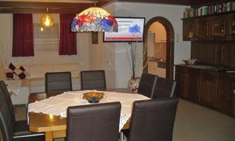 A cozy dining area with a large table and chairs. The colored glass lamp creates a warm atmosphere.