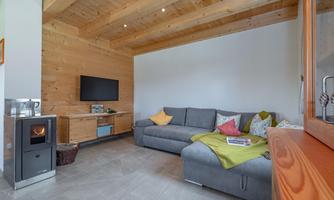 A modern living room with a gray couch and colorful pillows. A TV hangs on the wall and there is a small fireplace.