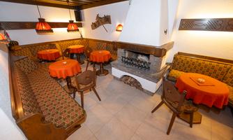 A cozy seating area in a mountain cabin with orange tables and a fireplace. The walls are decorated with traditional wooden paneling.