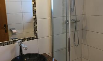 A modern bathroom with a shower cubicle and a stylish sink. The walls are designed with white tiles and a decorative border.