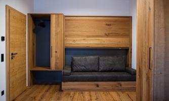 A modern room with a comfortable sofa and wooden cabinets. The walls are painted in neutral colors, giving the space a cozy atmosphere.