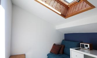 A cozy room with a blue sofa and a small table. A skylight provides plenty of daylight.