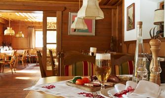 A cozy restaurant with wooden furniture and warm lighting. On the table are beers, a plate of vegetables, and tastefully set cutlery.