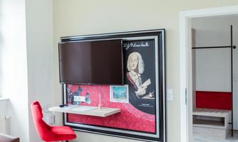 A modern room with a red chair and a table. On the wall hangs a piece of art as well as a television.