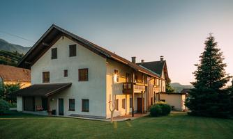 A charming multi-storey house in a green environment. The sun shines on the facade, surrounded by trees and meadows.