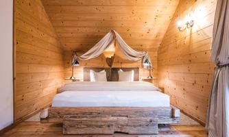 A stylish bedroom with wood paneling and a comfortable bed. Soft lighting and cozy decor create a relaxed atmosphere.