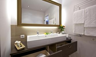 A modern bathroom with a double sink and a large mirror. Towels and a small flower decoration give the room a cozy atmosphere.