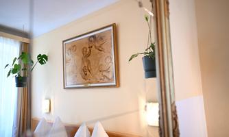 A cozy room with white cushions and a picture on the wall.  
Plants hang decoratively in the room.