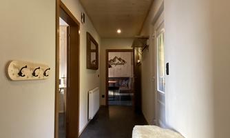 A bright hallway with wooden paneling and modern furniture. Hooks for coats and a large mirror are hanging on the wall.