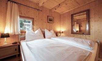 A cozy bedroom with wooden paneling and a large bed.  
Soft pillows and gentle light create an inviting atmosphere.