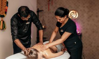 A relaxing massage setting with two therapists giving a massage to a woman. The atmosphere is calming and professionally designed.