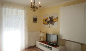 A bright living space with a cozy decor. There is a television, a lamp, and a piece of art on the wall.
