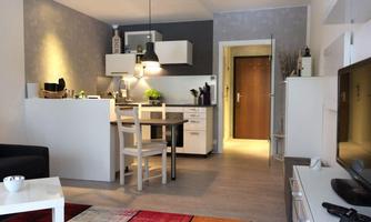 A modern kitchen with a dining table and bright furniture. The room has a cozy carpet and an inviting atmosphere.