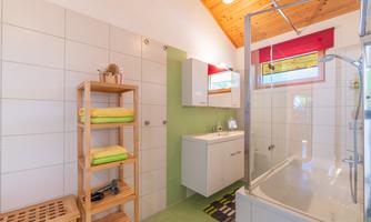 A modern bathroom with a shower cabin and a bathtub. Shelves with clean towels and grooming products are on the wall.