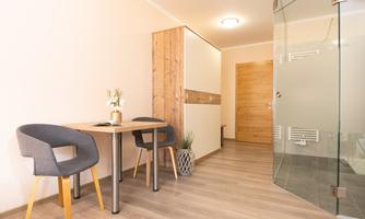 A modern room with a small table and two chairs. A glass partition creates an open and inviting space.