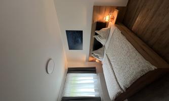 A cozy bedroom with a double bed and two nightstands. The window lets in plenty of light, and there is a calm, relaxed atmosphere.