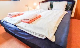 A cozy bedroom with a large bed and fresh towels. Soft light and a window create an inviting atmosphere.